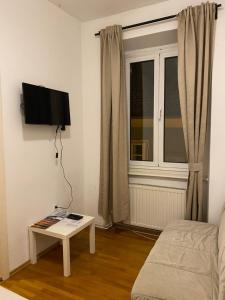 a living room with a couch and a tv and a table at Rooms and apartments Nokturno in Zagreb