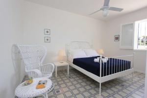 una camera da letto bianca con un letto e una sedia a dondolo di Sud Est Le Case di Elisa a Marina di Ragusa