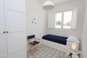 una camera da letto con un letto, una sedia e una finestra di Sud Est Le Case di Elisa a Marina di Ragusa