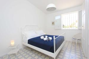 una camera bianca con un letto con una coperta blu di Sud Est Le Case di Elisa a Marina di Ragusa