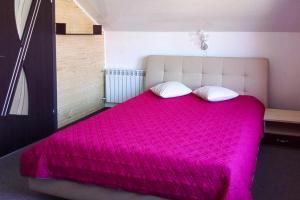 a large bed with a pink blanket and two pillows at Holiday complex, Swinoujscie in Świnoujście
