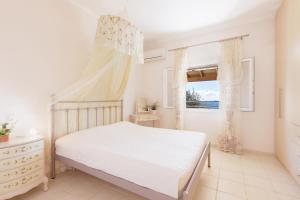 a white bedroom with a bed and a window at Villa Elia, Spartylas Corfu in Spartýlas