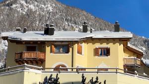 une maison jaune avec de la neige sur le toit dans l'établissement Funtanella, à Samedan
