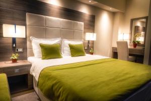 sypialnia z dużym łóżkiem z zieloną pościelą i poduszkami w obiekcie Hotel Tami Residence w Niszu