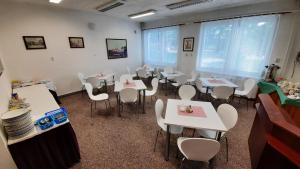 uma sala de jantar com mesas brancas e cadeiras brancas em Hotel Kristl em Pardubice