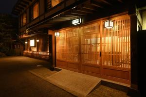 an entrance to a building with a gate at night at Ryokan Tamura in Kusatsu