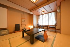 a living room with a table and a tv at Ryokan Tamura in Kusatsu