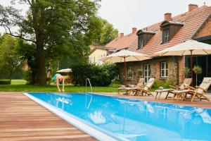 a person bending over a swimming pool next to a house at Gutshaus Stolpe in Stolpe