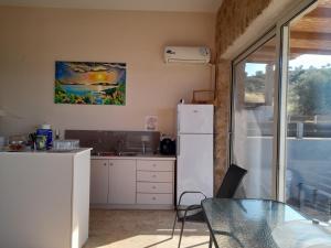 a kitchen with a table and a white refrigerator at Sol Pedra Villas in Skala Marion