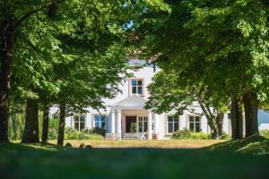 una casa blanca con árboles delante de ella en Relais & Châteaux Gutshaus Stolpe en Stolpe