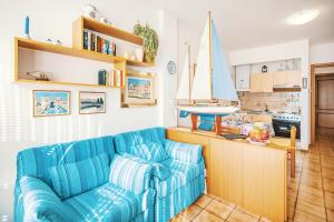 a living room with a blue couch and a kitchen at Una terrazza sul golfo di Ospedaletti by Wonderful Italy in Ospedaletti +11 photos