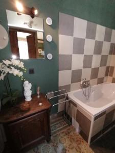 bagno con vasca, lavandino e specchio di Maison d'hôte Les Notes Endormie Chambre Secrète a Berzée