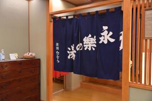a room with a blue curtain with asian writing on it at Ryokan Tamura in Kusatsu