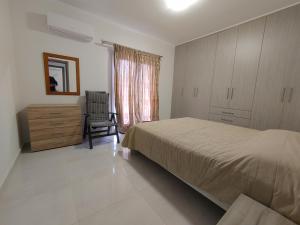 a bedroom with a bed and a dresser and a chair at Stefanos' Apartment in Litherés