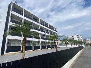 a large white building with palm trees in front of it at HYGGE Biimata in Nago