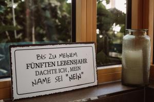 Un cartello seduto su un davanzale vicino a un vaso di Weingut Kollerhof am Eichberg a Leutschach