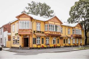 un bâtiment jaune avec des tables et des chaises dans une rue dans l'établissement Karusselli Apartment, à Pärnu