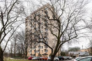 a tall building with cars parked in a parking lot at ShortStayPoland Darwina (B9) in Warsaw