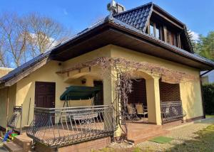 a small yellow house with a porch and a balcony at Dom nad jeziorem Sławskim in Lubiatów