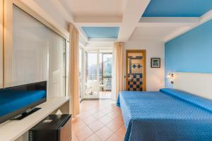 a bedroom with a blue bed and a television at Albergo La Margherita in Scala