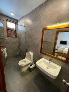 uma casa de banho com um WC, um lavatório e um espelho. em Lotus Lake Residence em Kandy