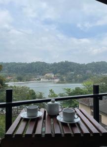 a table with two tea cups on top of a balcony at Lotus Lake Residence in Kandy