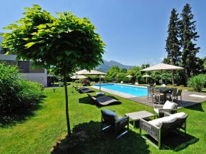 una piscina con sedie, tavoli e un albero di Hotel Ertl & mexican cantina salud a Spittal an der Drau