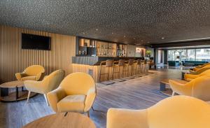 una sala de espera con sillas amarillas y un bar en HF Tuela Porto en Oporto