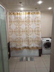 uma cortina de chuveiro na casa de banho com uma máquina de lavar roupa em SPACE Aparts and Rooms em Ecaterimburgo