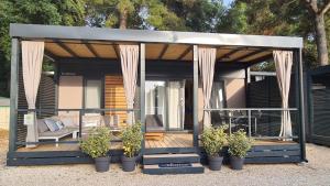 una casa pequeña con porche y algunas plantas en Hemy Casa - Lux Mobile Homes en Rovinj