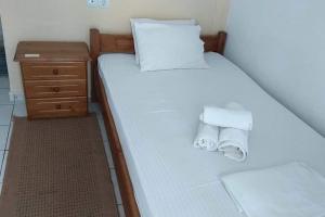 a bed with two towels on it with a night stand at Studio 10 minutes from the center of Heraklion. in Heraklio