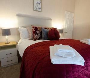 una camera da letto con un letto rosso e asciugamani di Hollicarrs - Bluebell Lodge a Riccall