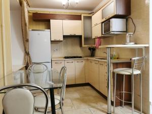 Chernigov City Centre Apartments في تشيرنيهيفسكا: مطبخ مع طاولة وكراسي وثلاجة