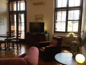 uma sala de estar com uma televisão, cadeiras e uma mesa em Apartment Parliament park em Belgrado