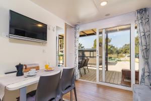 a dining room with a table with chairs and a television at Perla - Lux Mobile Homes in Rovinj +12 photos