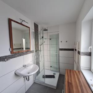 ein weißes Badezimmer mit einem Waschbecken und einem Spiegel in der Unterkunft Wohnung "Orther Hafen" in Bannesdorf auf Fehmarn in Fehmarn