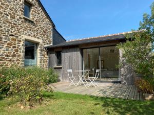 a patio with chairs and a table in front of a building at La Chambre de Claire in Les Iffs