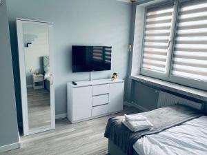 een slaapkamer met een televisie op een dressoir met een bed bij 2Lustra in Białystok