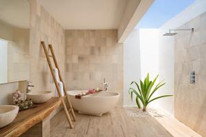 马纳杜岛Kuredhivaru Resort and Spa - Maldives的浴室设有2个水槽、浴缸和植物