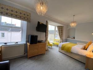 a bedroom with a bed and a flat screen tv at Sunny Bank Guest House in Tenby