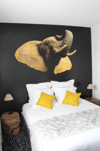 een olifantenkop aan een muur boven een bed bij Au Palmyre Hôtel in La Palmyre
