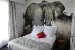 a bedroom with an elephant painting on the wall at Au Palmyre Hôtel in La Palmyre
