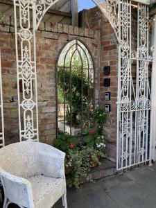 a white gate with a chair and some flowers at Coswarth House in Padstow