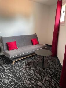 a couch with two red pillows in a room at Au Palmyre Hôtel in La Palmyre