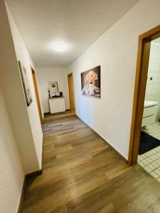 a hallway with white walls and wood flooring at EasyStay#3 Comfort Suite Ferienwohnung in Kliniknähe mit Boxspringbett & Netflix in Bad Oeynhausen
