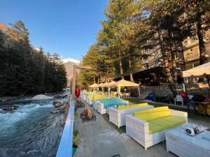 a row of tables and chairs next to a river at Moksha Riverside Resort in Kasol