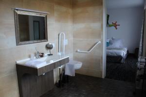 a bathroom with a sink and a toilet and a bed at Au Palmyre Hôtel in La Palmyre