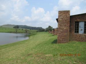 a brick building next to a body of water at Elandskloof Trout Farm in Dullstroom