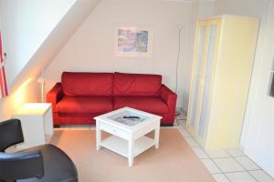 - un salon avec un canapé rouge et une table dans l'établissement Nordlicht, à Wyk auf Föhr
