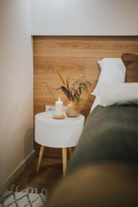 a white table with a candle on it next to a bed at Apartamenty Boszkowo Lake Harbor in Boszkowo